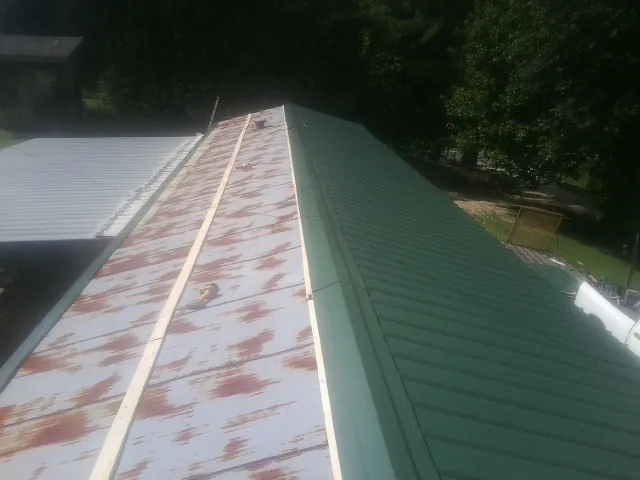 Old rusted panels beside newly installed green metal roofing — Wind Damage Roof Repair by Roofing Brothers in Briarcliff Manor
