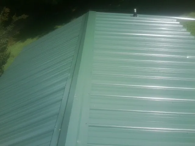 New green metal panels meeting at the ridge of a roof — Flat Roof Repair work by our crew in Briarcliff Manor