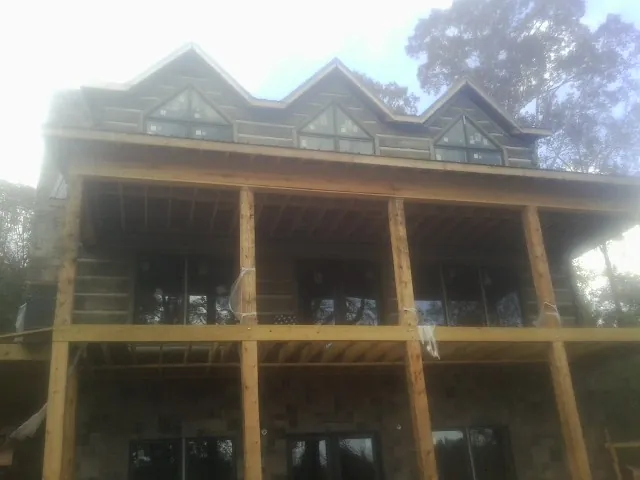 Dormers and porch framing on a large log home under construction — Roof Coating work by our crew in Briarcliff Manor