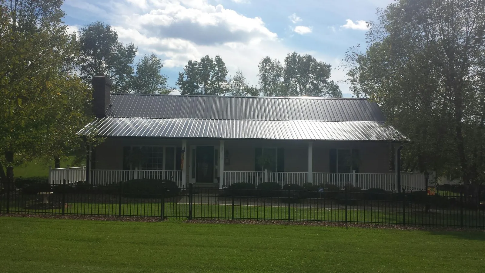 Gray metal roof on a brick ranch with a full width front porch — Gutter Guard Installation work by our crew in Briarcliff Manor