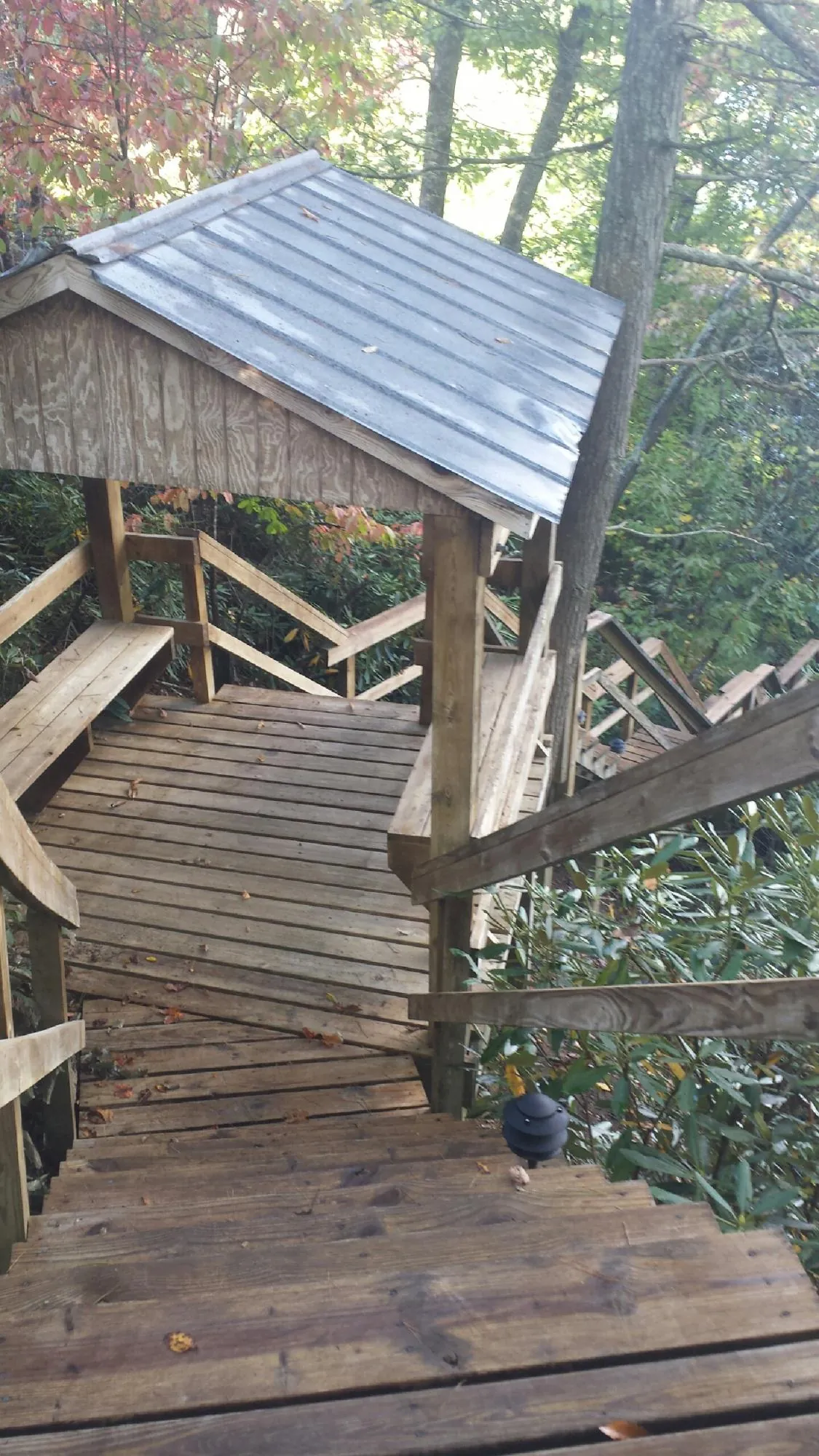 Metal roofed shelter over wooden steps on a wooded walkway — Skylight Repair & Installation work by our crew in Briarcliff Manor