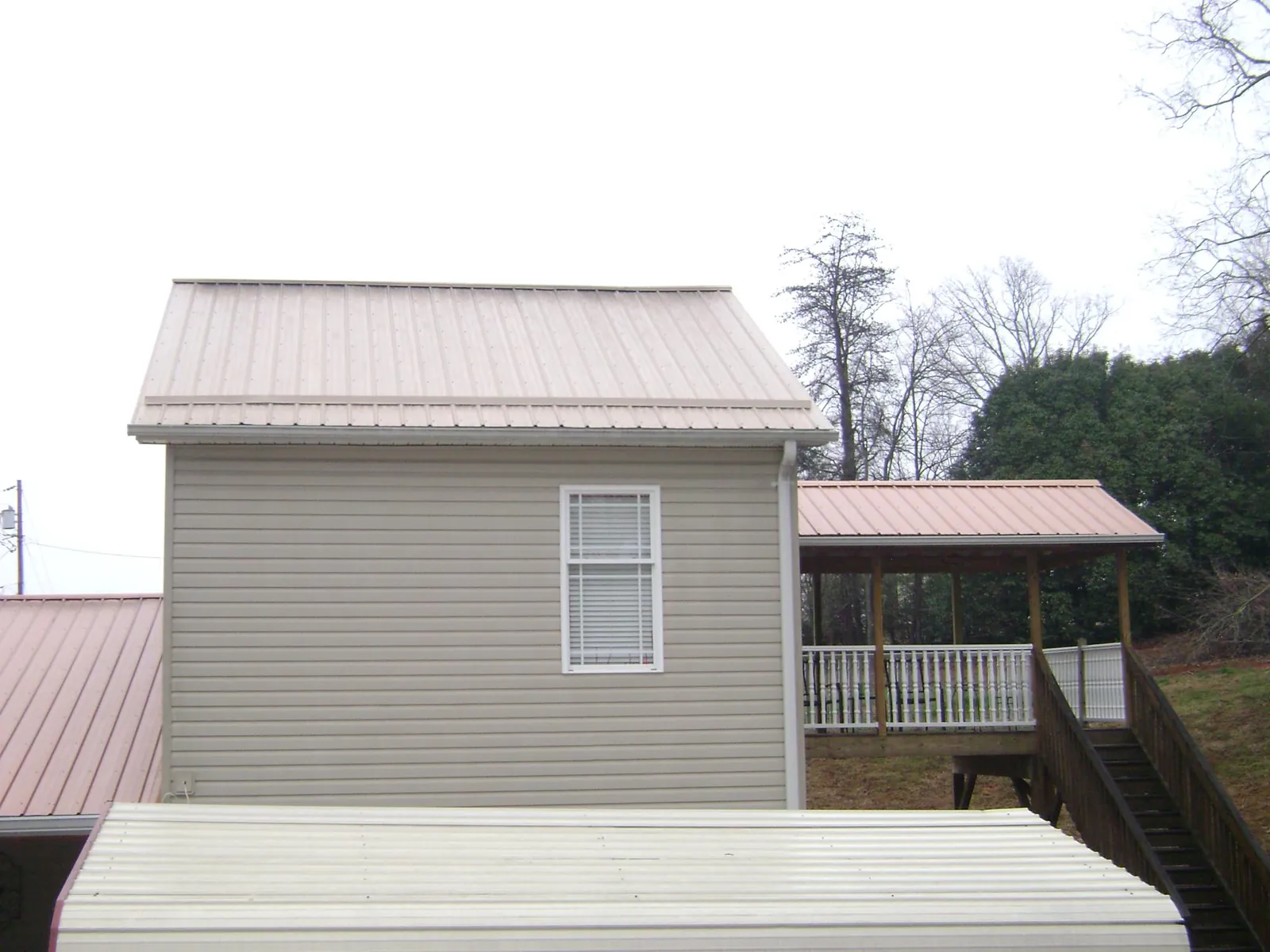 Tan metal roofs on a two story addition and attached porch, from a Roof Replacement job in Briarcliff Manor