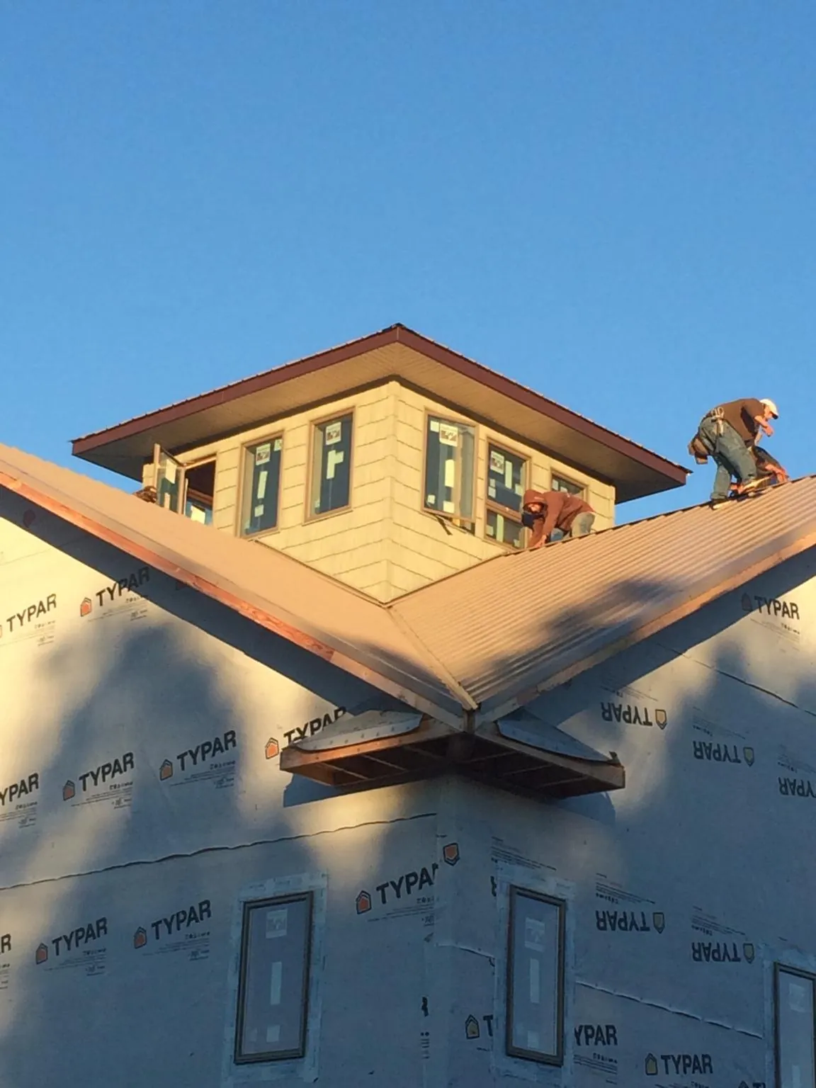 Roofers working around a rooftop cupola on a new metal roof at sunset — Roof Waterproofing in Briarcliff Manor by Roofing Brothers
